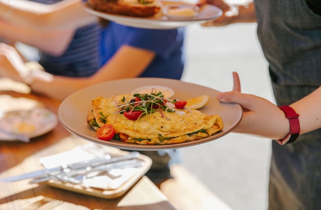 Person holding a plate with an omelette at Alberta's, Māpua Wharf.