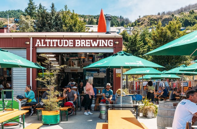 The colourful exterior of Altitude Brewing surrounded by large green umbrellas.