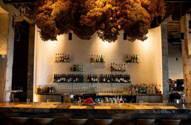 A large bar with a large dried flower arrangement hanging from the ceiling.