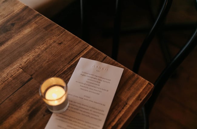 Arden menu on a table with candle.