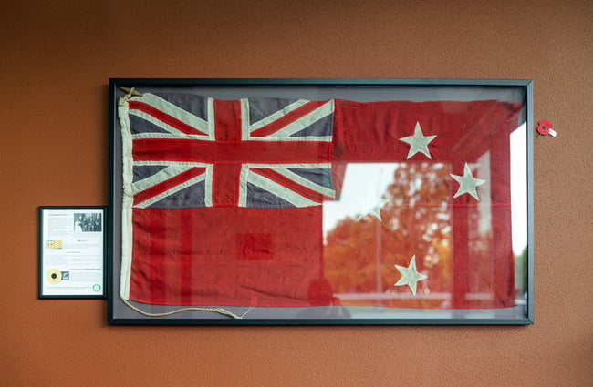 An old red and blue flag framed on a wall.