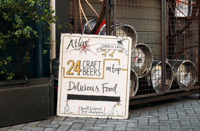 A sign promoting 24 craft beers on the ground outside Atlas Beer Cafe Queenstown.