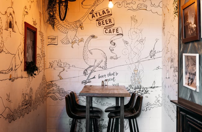 Hand drawings on wall behind a high table and chairs.