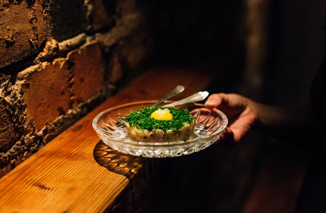 Someone holding a dish of beef tartare at Bar Celeste.