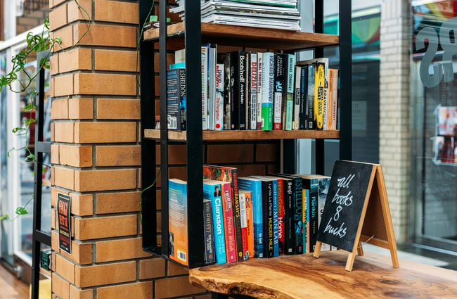 Books on shelves inside Bay Barbers Tauranga.