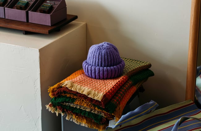 A close up of a purple beanie on a blanket.