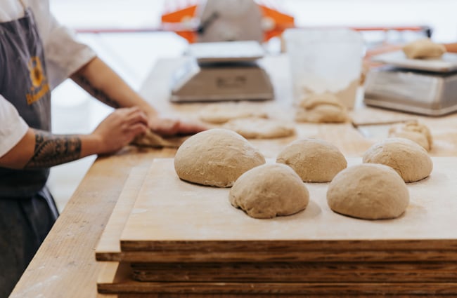 Baker working with dough in balls.