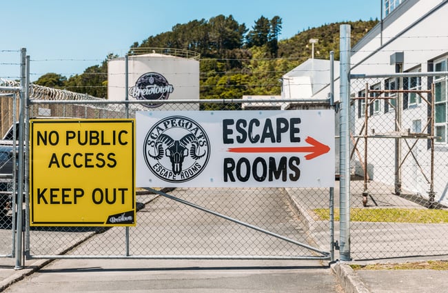 Signage that says 'Escape Rooms' on a fence.