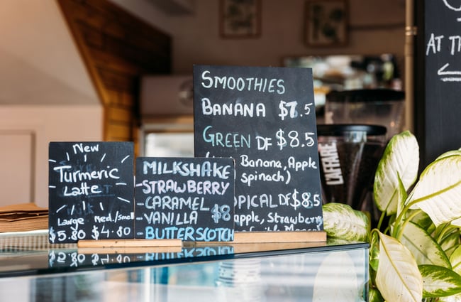 A close up of chalkboard menus promoting smoothies on top of a cafe counter.