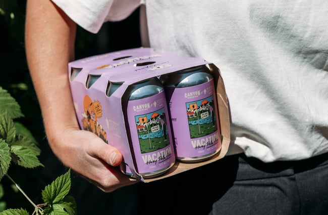 A six pack of beers under a person's arm.