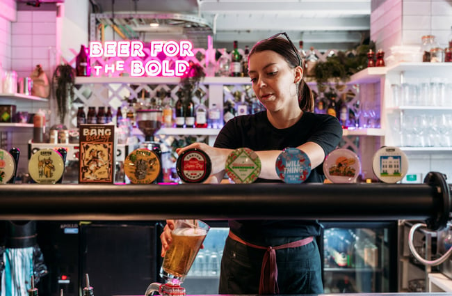 A staff member pouring beer behind a bar counter.