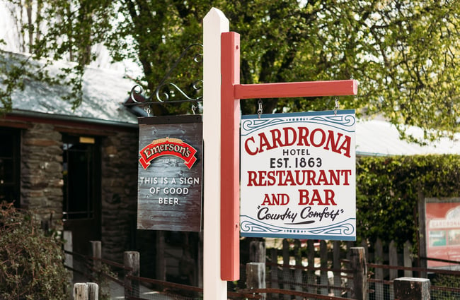 An Emerson's beer sign and Cardrona Hotel sign hang on a post outside Cardrona Hotel.