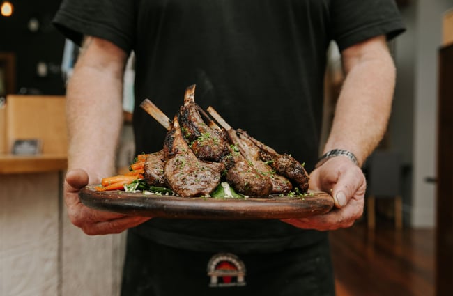 Man holding plate of lamb chops at Carnegie's Restaurant and Bar, Fairlie.