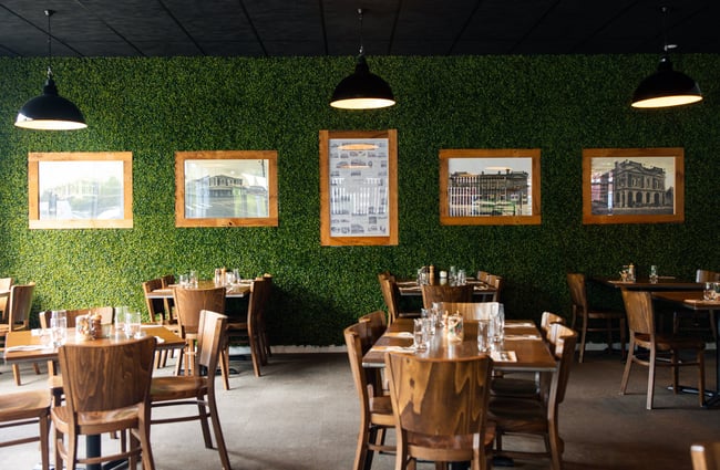 A fake green wall inside a large restaurant.