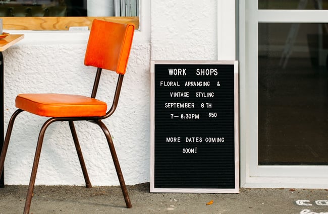 A leather orange chair outside next to a black letter board.