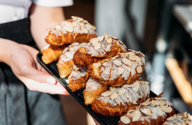 Hands holding a plate of almond croissants.