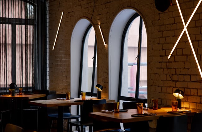 Tables and chairs lined up against windows inside Culprit restaurant in Auckland.