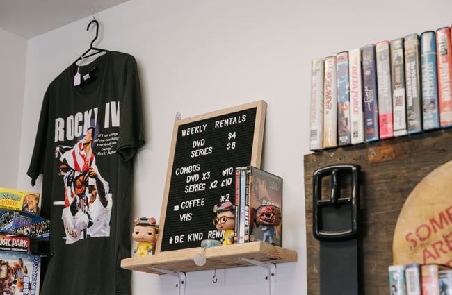 Price board and t-shirt hanging on the wall at Dead Video in Lyttelton.