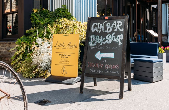 A blackboard sign promoting a gin bar from the street.