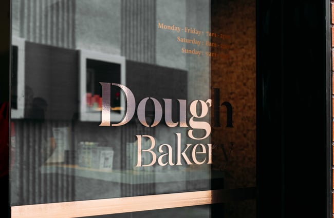 A close up of the Dough Bakery sign on a glass window.