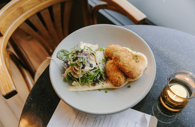 Birds eye view photo of a salad and crumbed food on a grey plate.