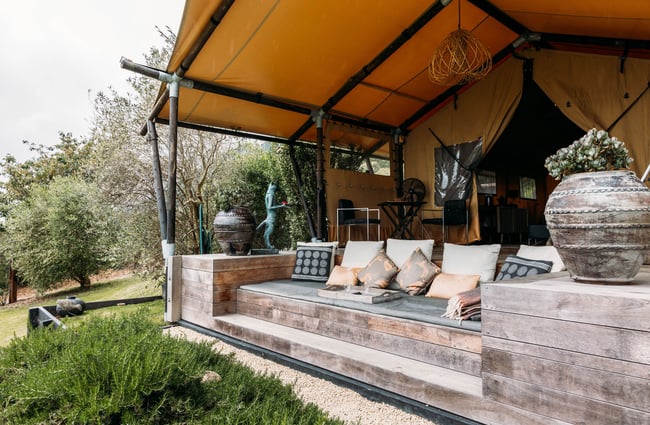 An outdoor couch in front of a glamping tent.