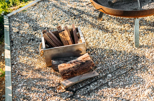 A small box of firewood next to a BBQ.