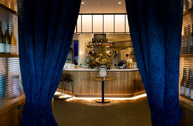 Entrance to Earl in Christchurch with deep blue velvet curtains and a floral centerpiece