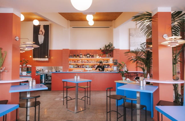 A view of the bar from inside the restaurant with its orange walls and bright blue furniture.