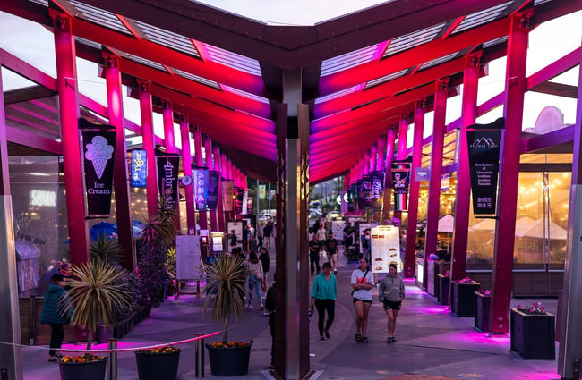 Looking down the length of Eat Streat in Rotorua, illuminated by pink lighting.