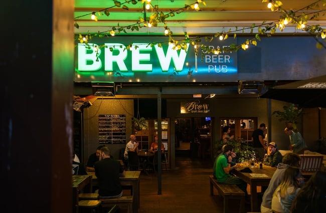 'BREW' in large green illuminated letters above the entrance to the pub.
