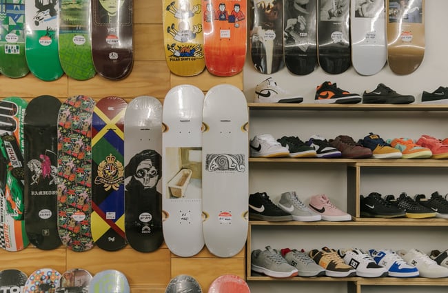Close up of wall-hung skateboard decks and sneakers on shelves at Embassy.