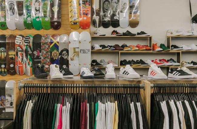 Sneakers and t-shirts on display and skateboards mounted on the wall behind inside Embassy.