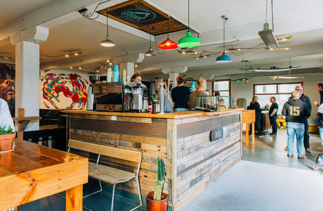 Interior view of the cafe with people standing around at Escape Coffee Roasters, New Plymouth.