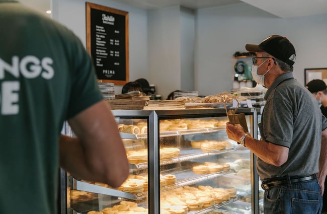 A man wearing a mask ordering pies at the counter of Fairlie Bakehouse.