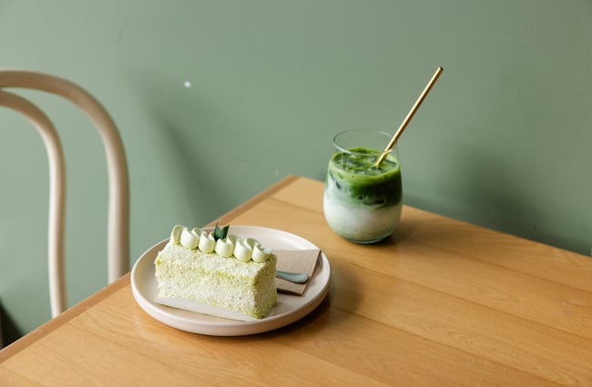 A close up of a dessert and green juice on a table.