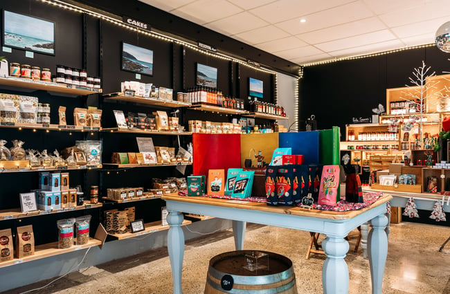 Overview of artisan food shop with products on shelves and products highlighted on table in the middle