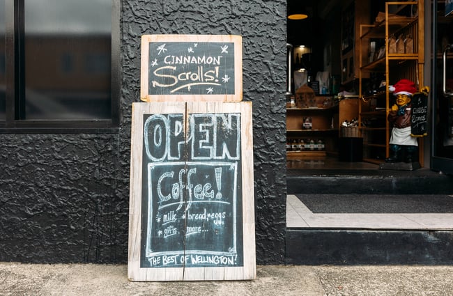 Open sign outside food shop with "cinnamon scrolls" written on it