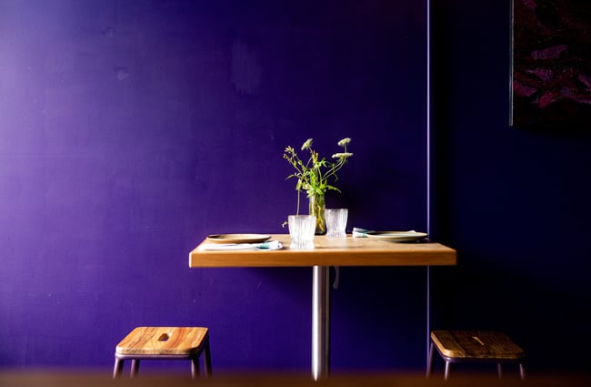 A table setting next to a blue / purple painted wall.