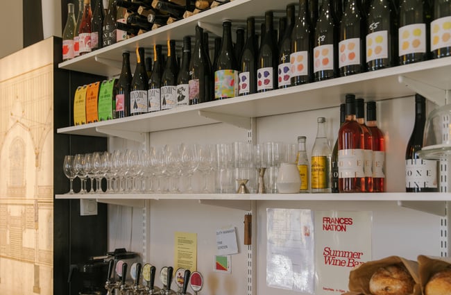Wine bottles and glasses on display on shelves.
