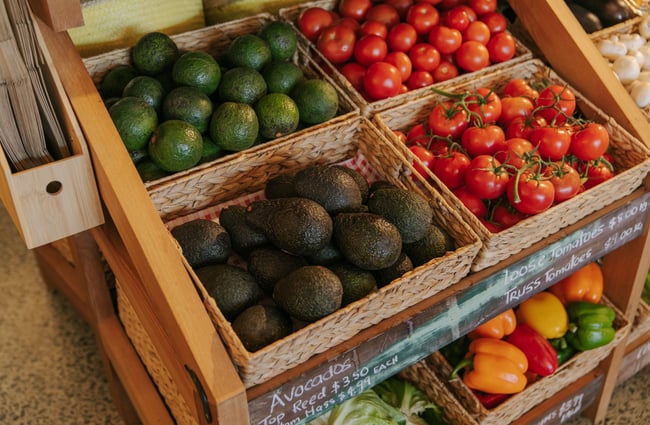 Avocados and tomatoes on display in boxes.