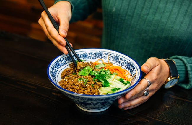 A customer holds bowl of noodles and mince at Garden Place Noodle Bar, Hamilton.