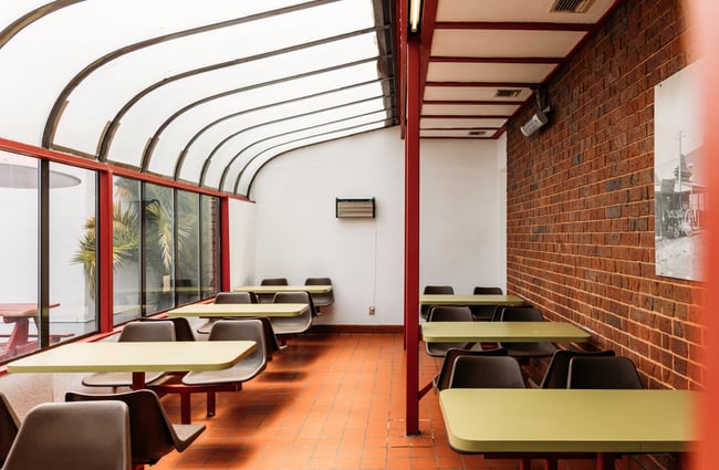 A covered area with retro brick and green coloured seating.
