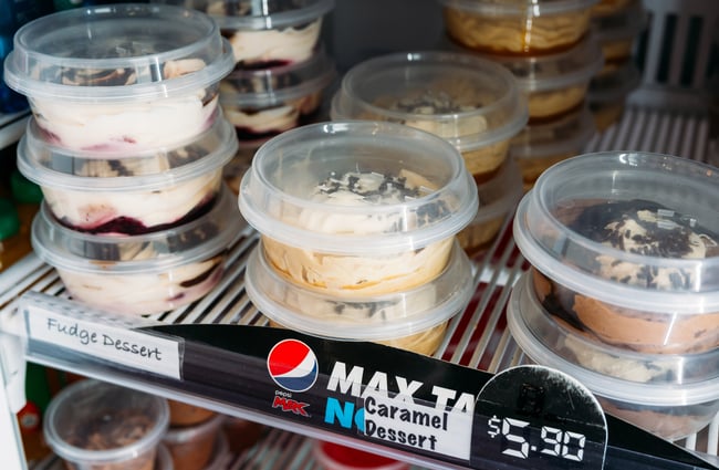 A close up of desserts in plastic containers in a fridge.