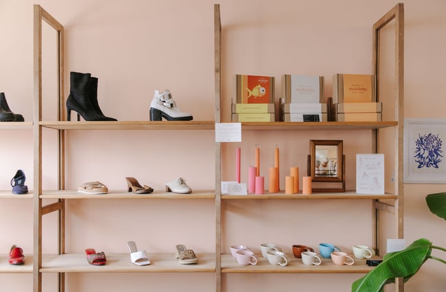Colourful shoes and candles on shelves set against a peach wall.