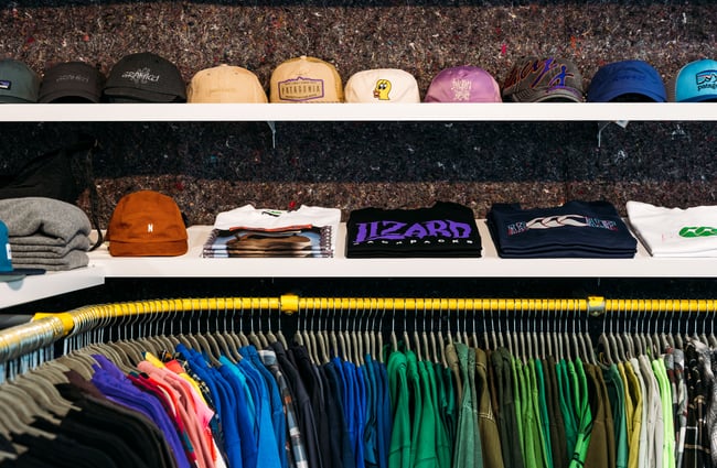 Colourful t-shirts and caps on display on shelves.