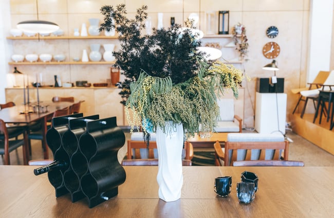 A white tall vase with a dried flower bouquet on display in the store.