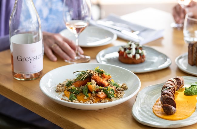 Close up of two dishes and a half-empty bottle of Greystone Rose on a dining table at Greystone Wines in North Canterbury.
