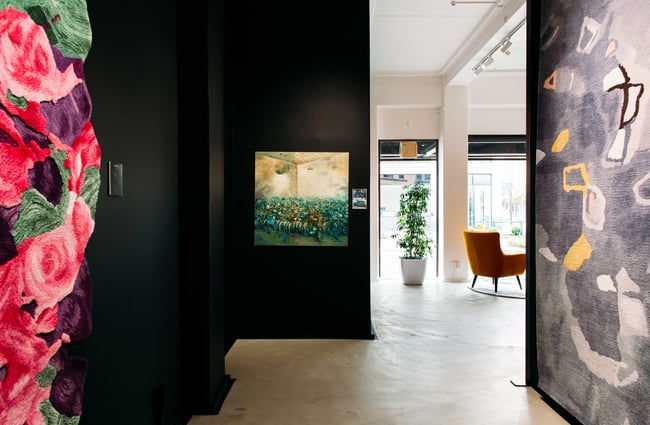 A small painting on display against a black wall.