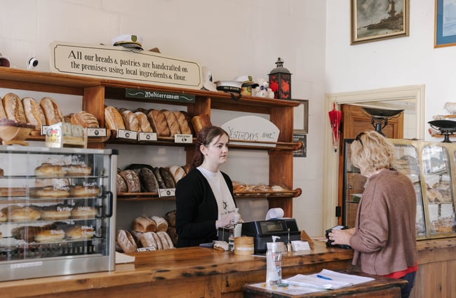 Woman serving a customer at the bakery at Deja Moo & Harbour Street Bakery in Ōamaru.